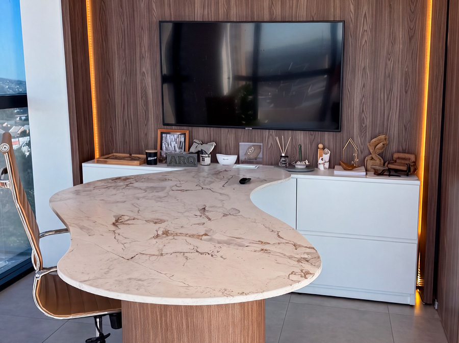 Mesa de reunião em mármore com painel de madeira no escritório de Marina Maiorki
